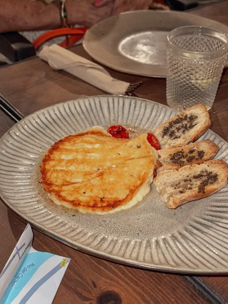 Plato con queso provolone y tostas servido en una mesa de madera.