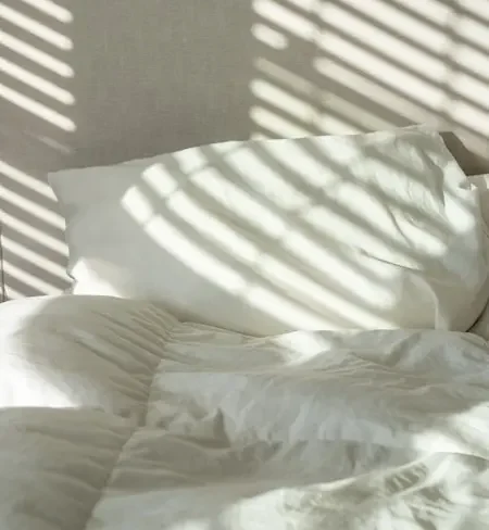 Luces y sombras de una ventana sobre una cama.